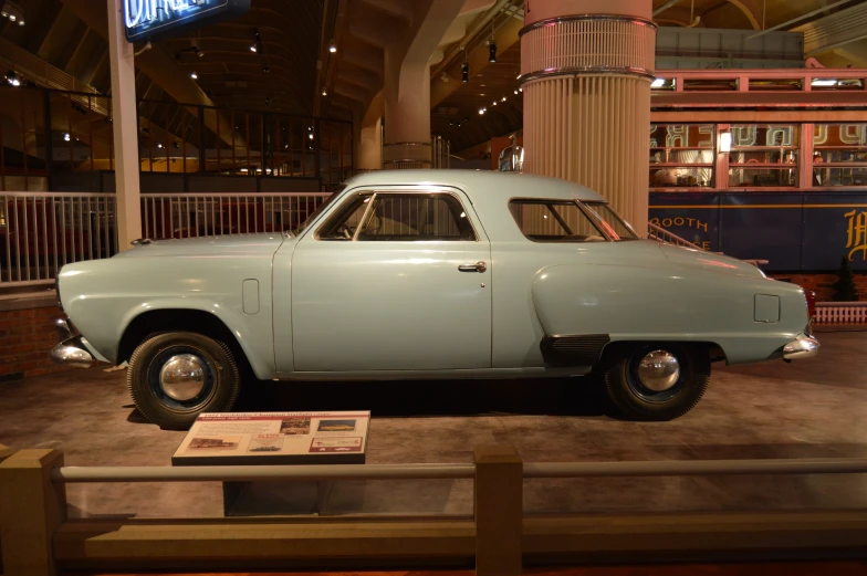 a small blue car sitting in a museum exhibit