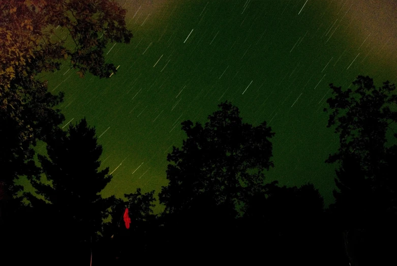 a very dark night sky with a green and yellow light