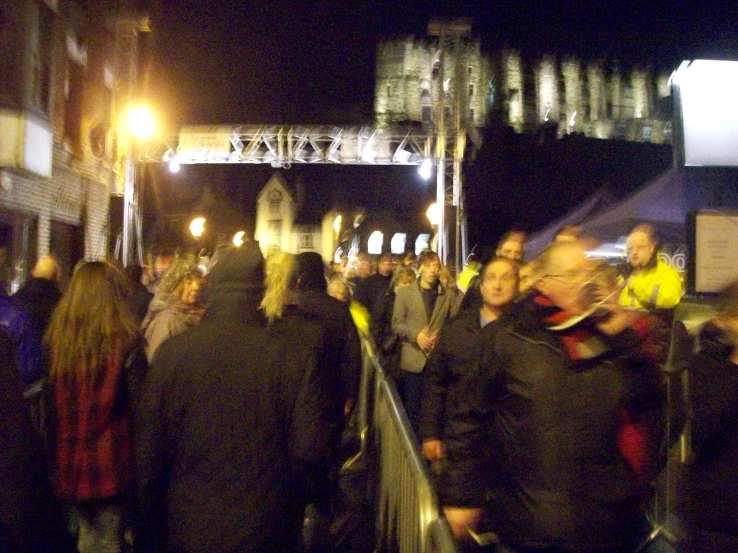 many people walking on the sidewalk in a city at night