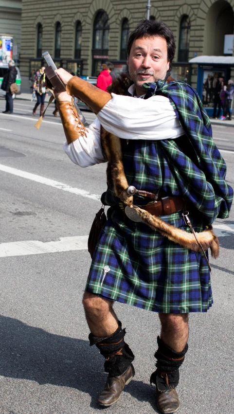 a man in a kilt holds an animal on a stick