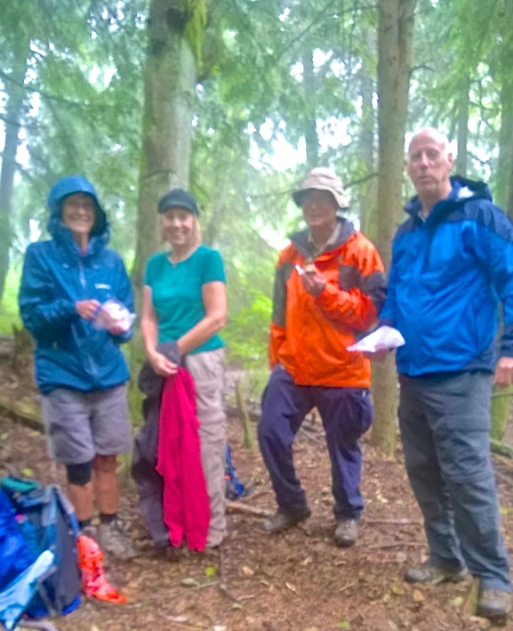 four people standing near a backpack with a frisbee in their hand