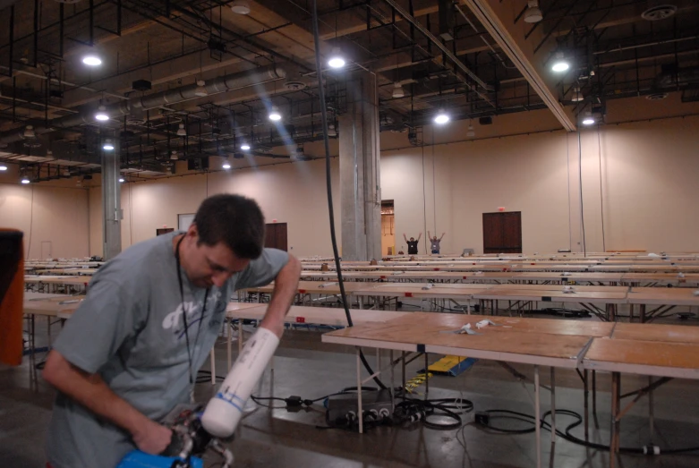 a man fixing some kind of object inside of an empty hall