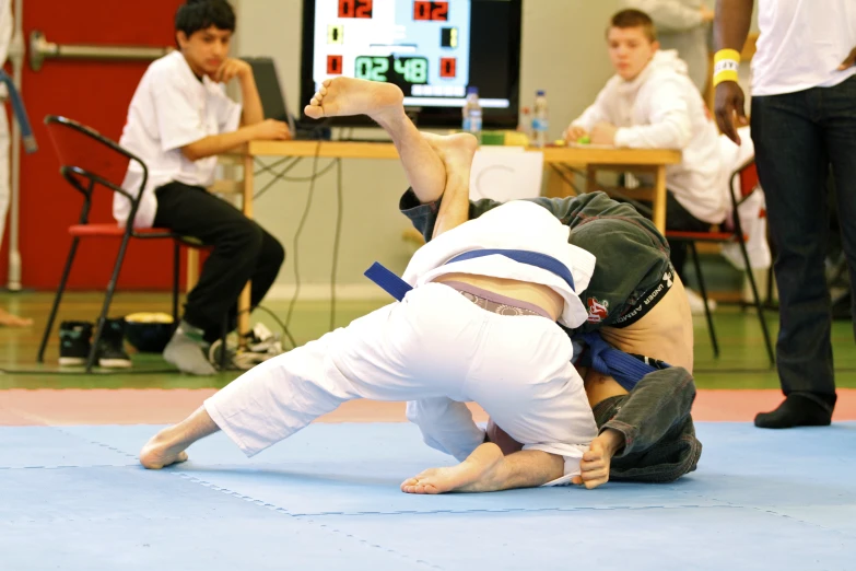 two young men in white and black outfits are doing karate
