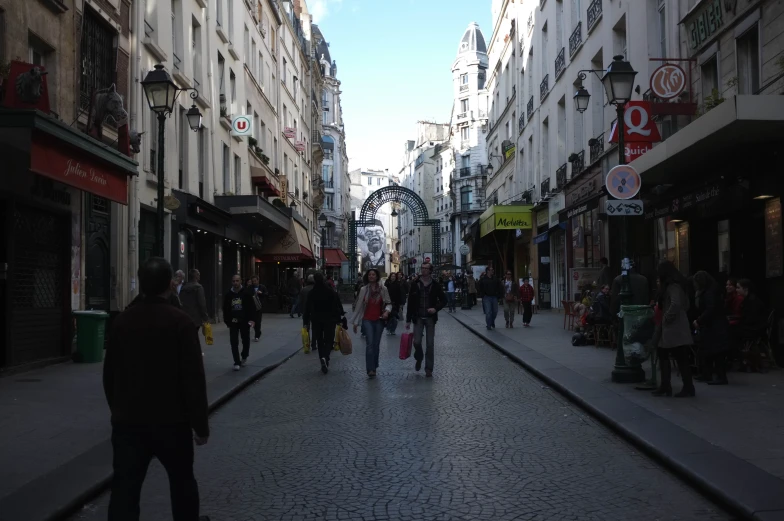 people walk down an urban street, including buildings and shops