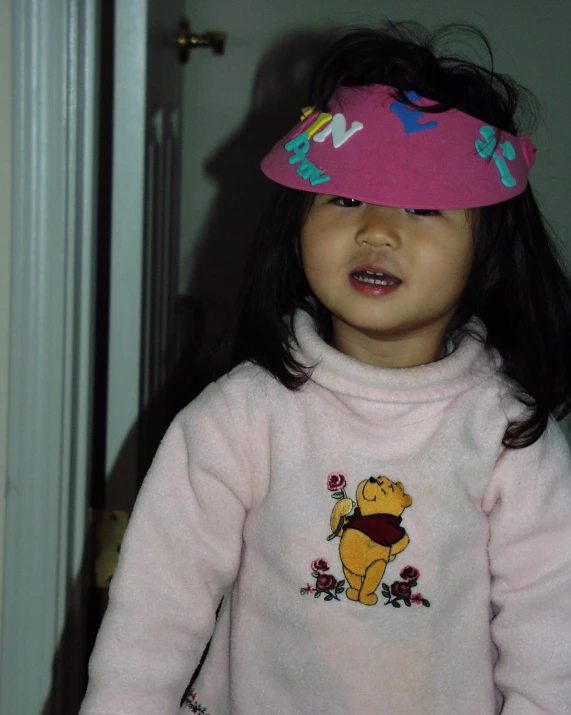 the little girl in the pink winnie the pooh hat is smiling