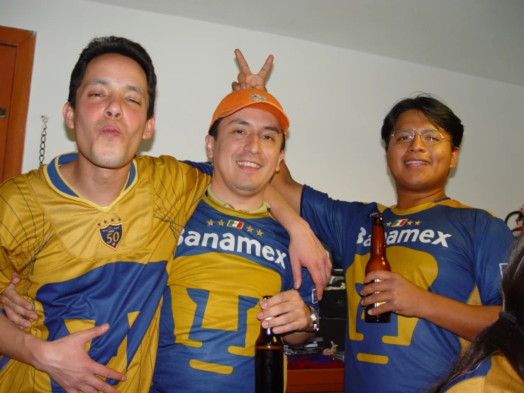 three young men standing together in matching blue and yellow shirts