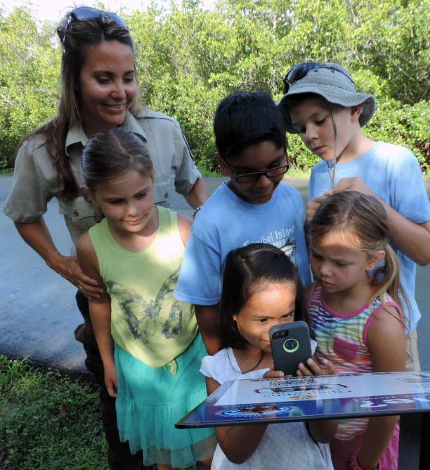 a group of children standing around a little girl taking a picture