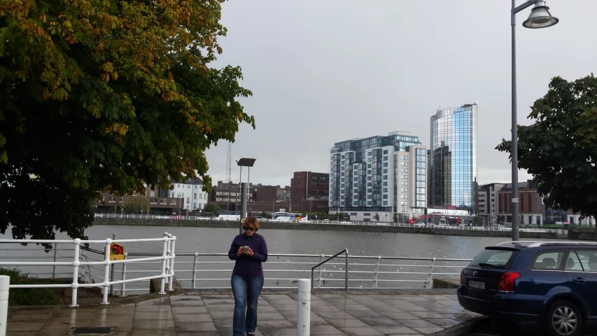 a lady is standing on a pier by some water