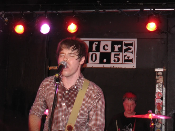 a man that is playing a guitar with other people in the background