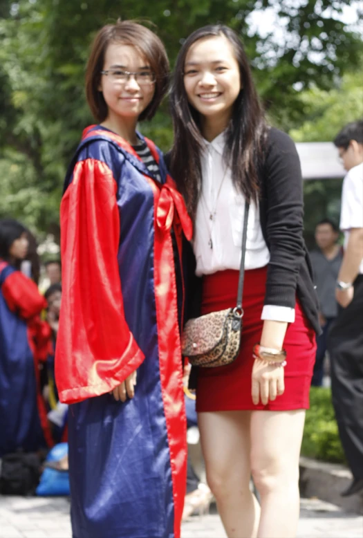 two women dressed in graduation attire posing for a po