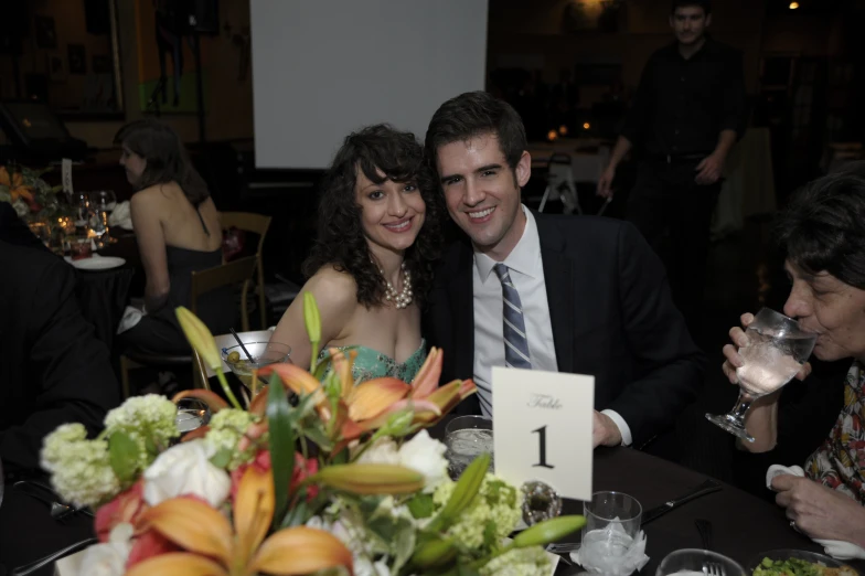 a young man and woman seated at a table at an event