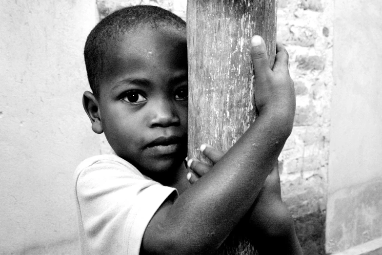 a boy is peering through the corner of a pillar