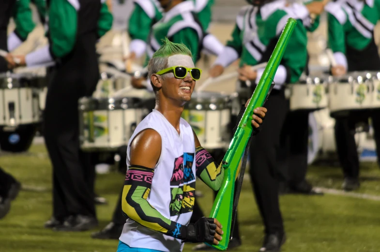 a group of drummers with a band holding green instruments