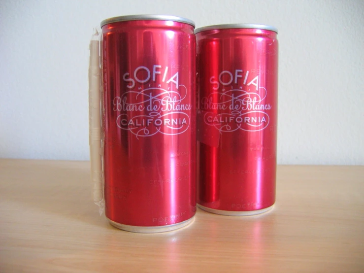 two soda cans, one red, are on a table