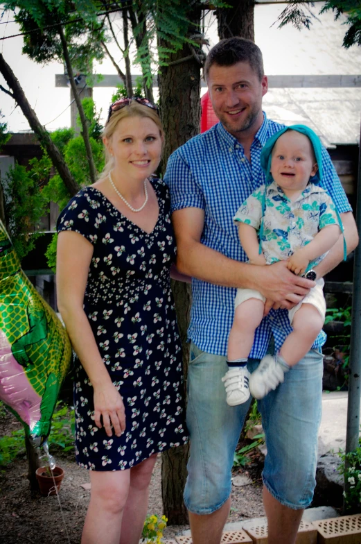 a man with glasses holding a baby and woman