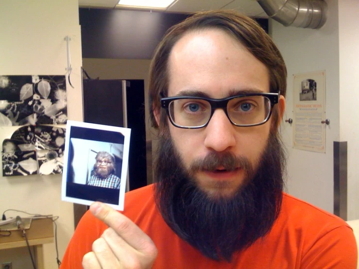 a man holding up an image of himself with a beard