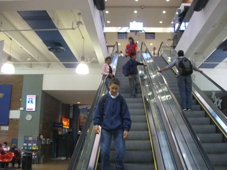 a boy is riding down an escalator in a public building