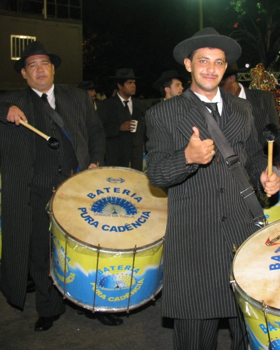 a group of men standing around a drum and a man in top hat