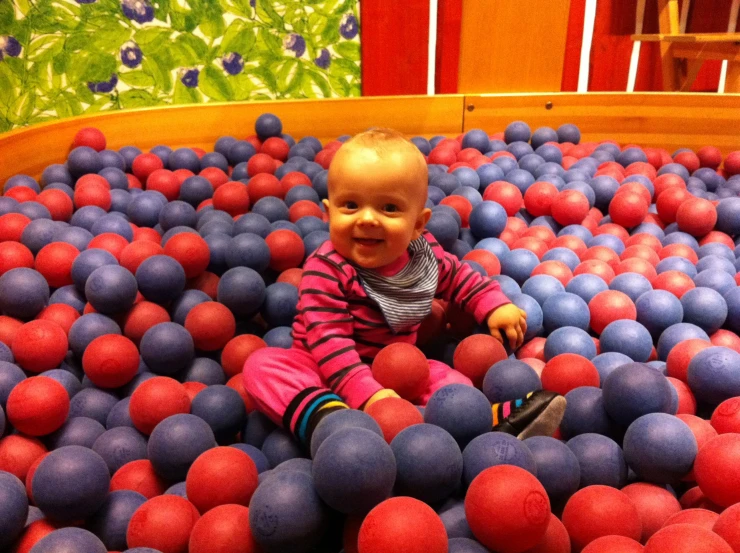 a baby sitting on a ball pit in a room