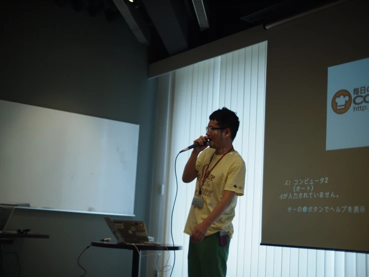 a man on a stage with a microphone and laptop