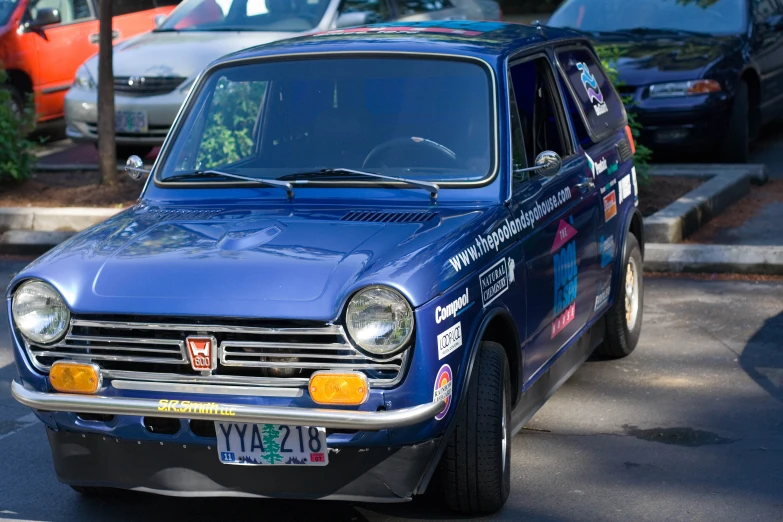 the small car is parked at the curb next to other cars