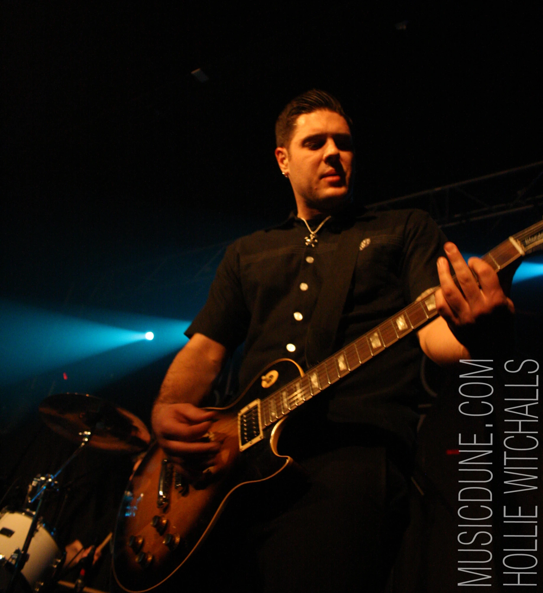 a man is playing a guitar with blue light behind him