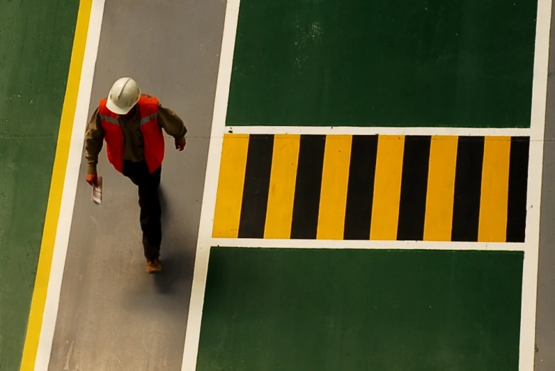 a man walking down the road with a hardhat on his head