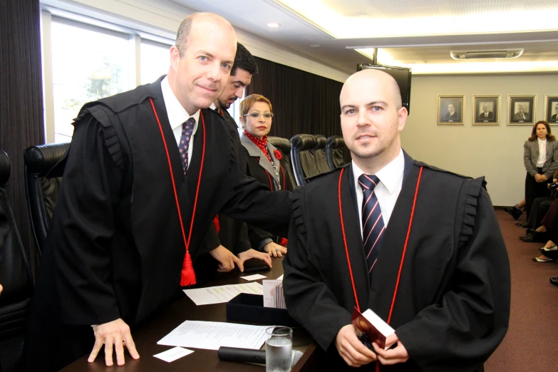 a man in a robe standing next to a man in a suit at a ceremony