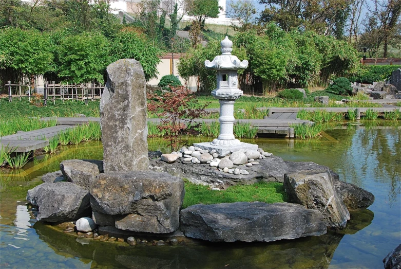 some rocks and an old water spout in a pond