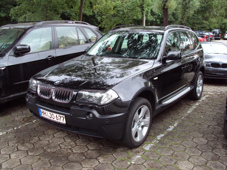 two cars parked in a parking lot in front of trees