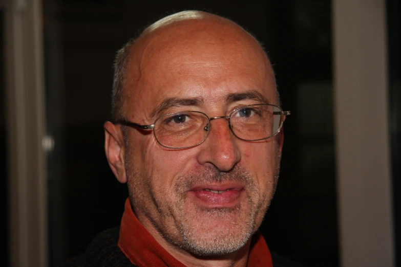 a balding man with glasses and an orange tie