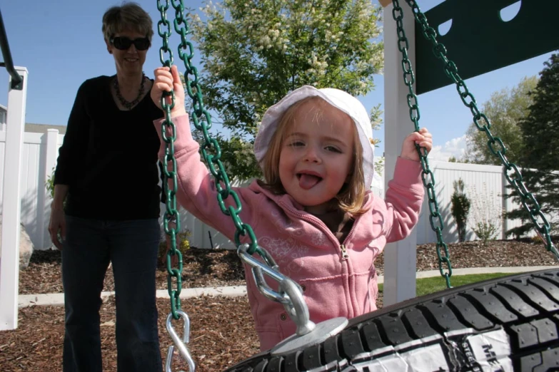 a  smiles while being held on a tire swing