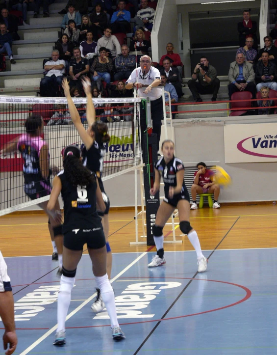 a volleyball player reaching for the ball while her teammates look on