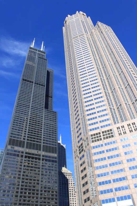 two tall skyscrs stand close together in front of the blue sky