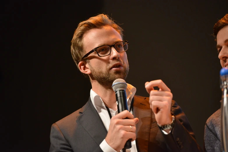 a man holding a microphone and another man with a tie