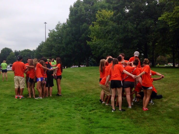 a bunch of people standing around each other in the grass