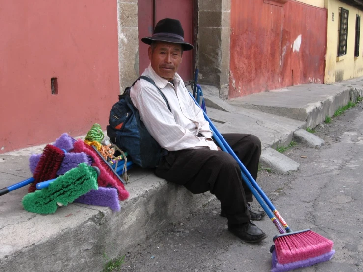 man sitting on the curb with broom and mop