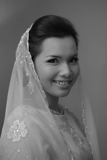 an asian bride smiles as she poses for the camera