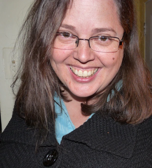 a woman in a sweater with glasses smiling