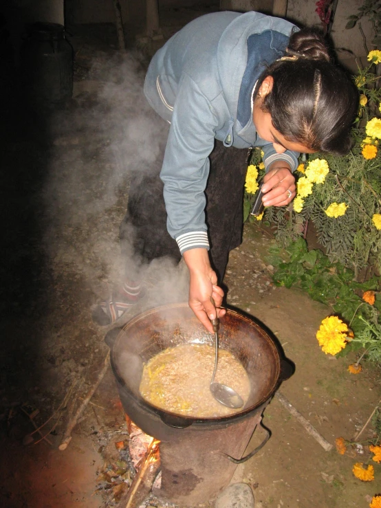 a woman stirring soing into a pan and a flower bush