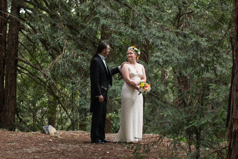 a married couple posing for a po in the woods