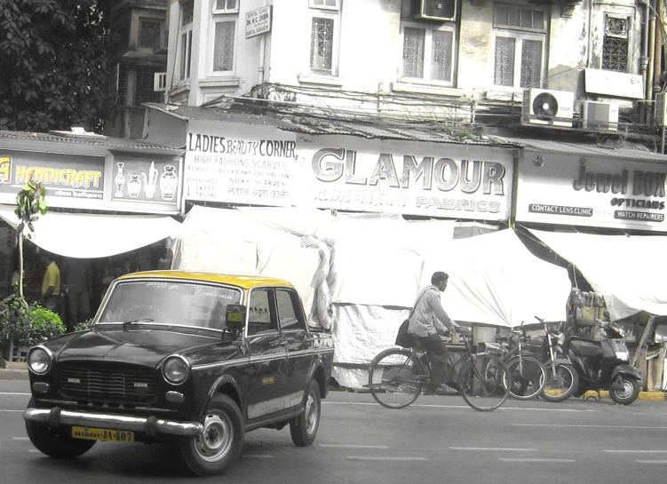 an old car is driving down the street in front of tents