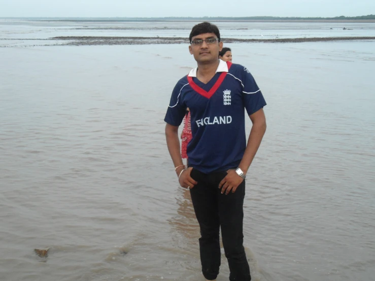 a man stands in the water wearing a shirt with england on it