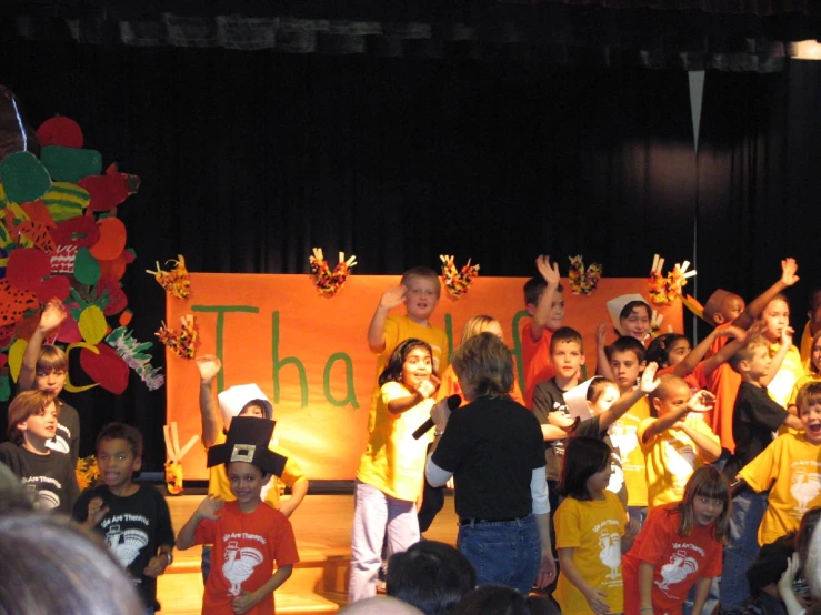 children singing on stage with a banner behind them