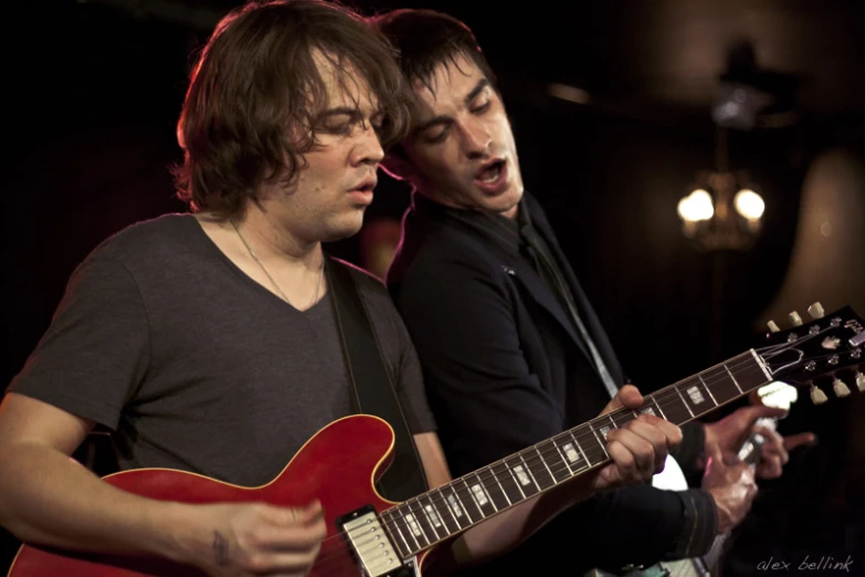 two men are playing music with red guitars