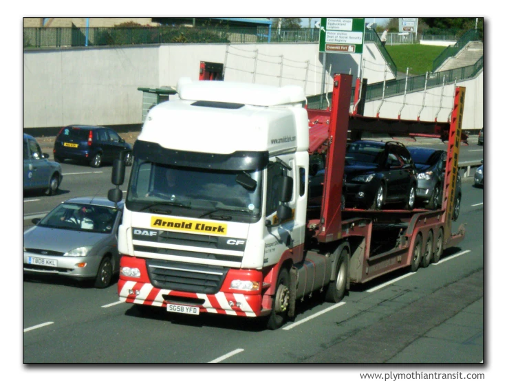 the cab of a truck with three cars in it drives on a road