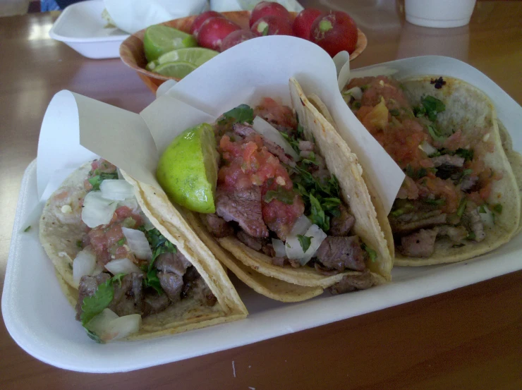 three tacos, one with meat and other on paper