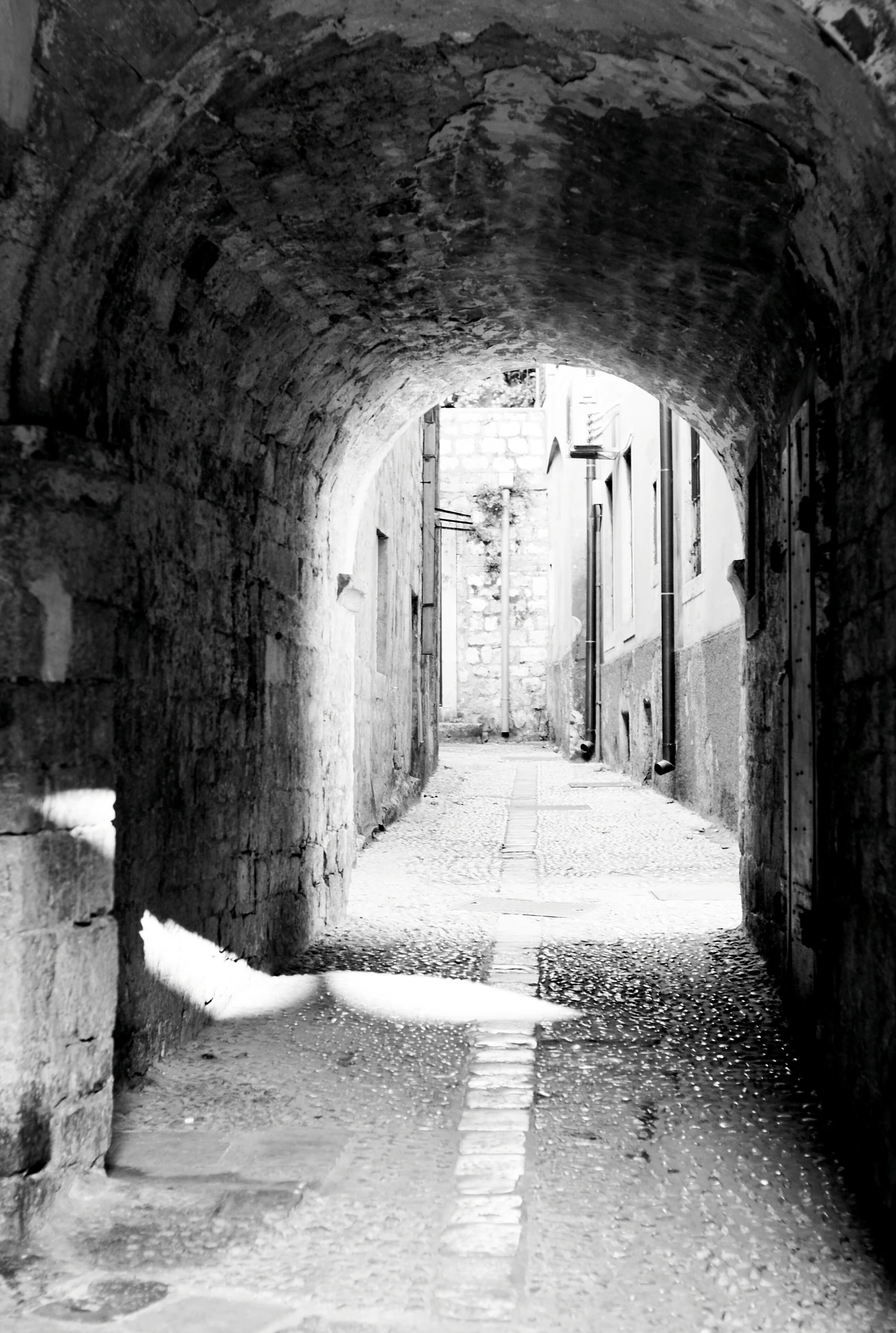 an empty stone alley leading to buildings