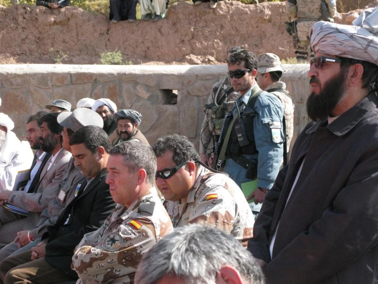 military men, including one of them wearing a military uniform, sit together