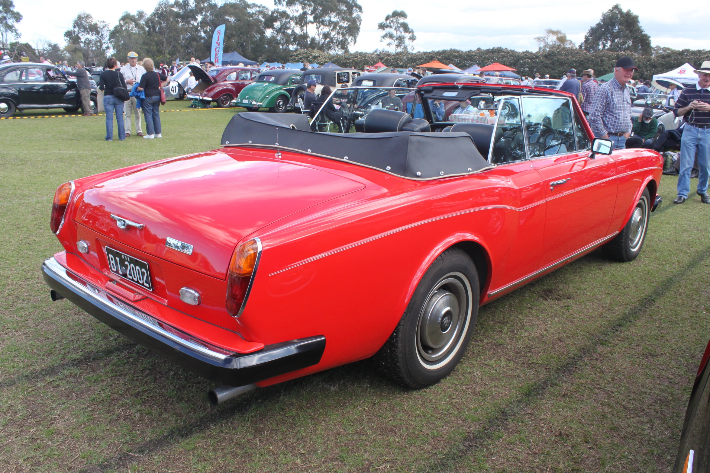 a red vintage sports car is parked at a classic car show